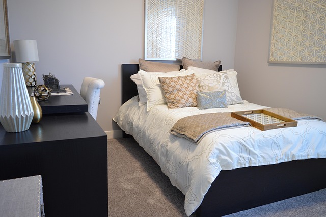 bedside table with lamp, book and small tray in minimalist neutral bedroom